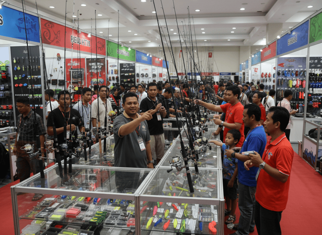 Editorial photo for a Malaysian fishing news website: Malaysian fishing expo with rows of modern rods, reels and tackle displays, enthusiastic anglers browsing, realistic event photography, no brand logos, no text